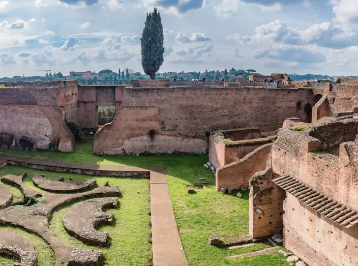 Ancient ruins on Palatine Hill in Rome with crumbling brick walls, stone foundations and grassy pathways overlooking the historic city skyline