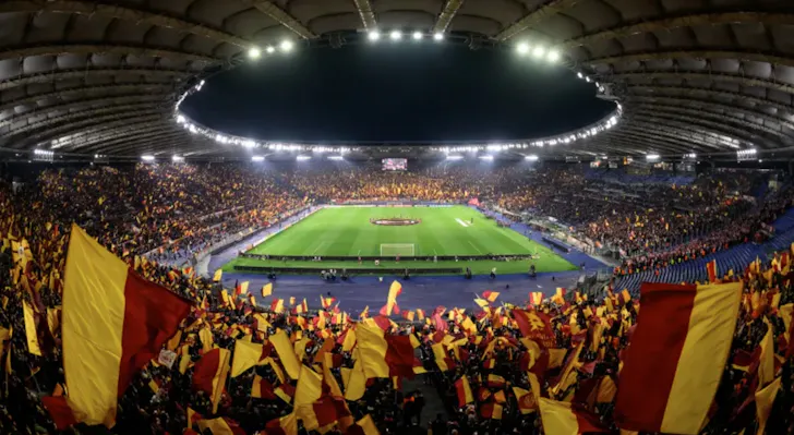 A football match at Stadio Olimpico in Rome with AS Roma fans and flags lit up at night