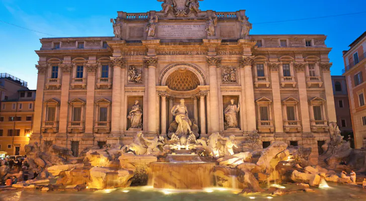 The spectacular Baroque style Trevi Fountain with its sculptures and clear water lit up in the evening in Rome
