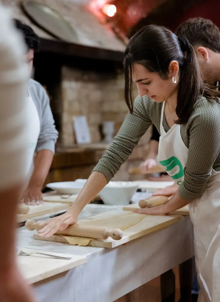 Someone in a cooking class in Rome rolling out fresh sheets of handmade pasta