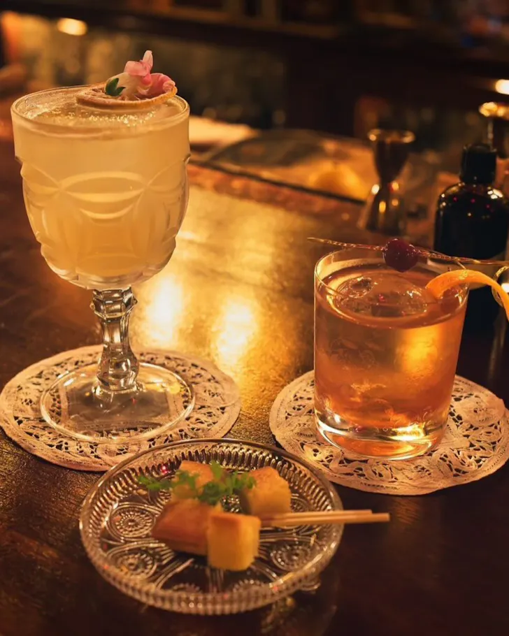 Two cocktails in vintage glassware on lace doily coasters at Bible Club Osaka.