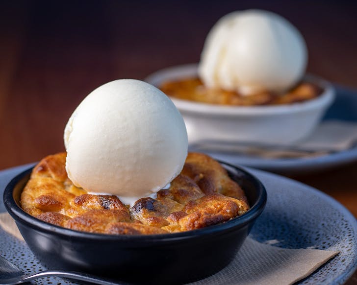 Two giant skillet cookies topped with a large sphere of vanilla icecream. 