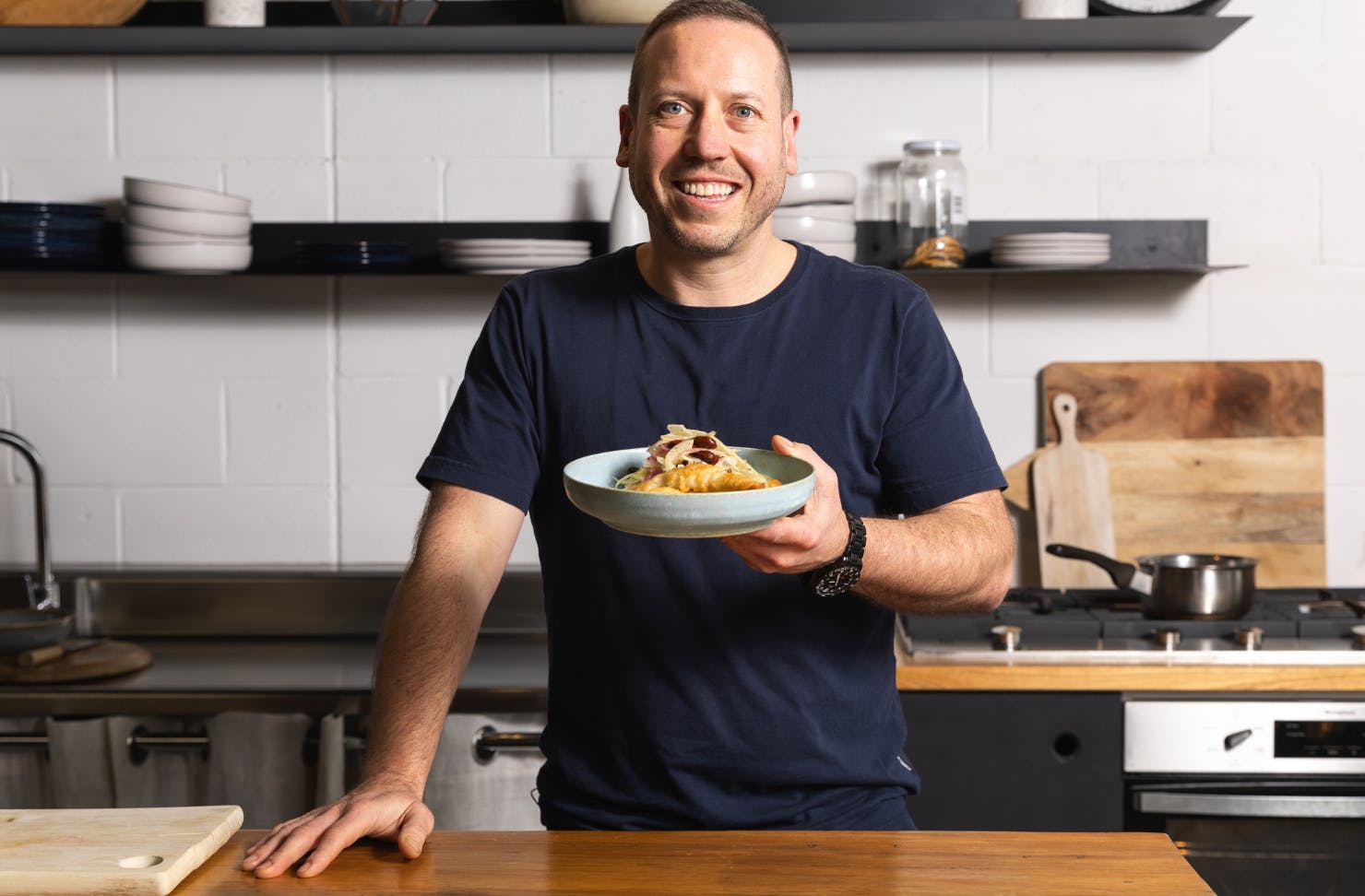Daniel Wilson holding plate of food in a kitchen