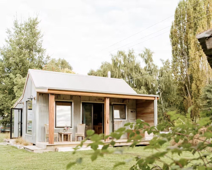 An exterior view of Birdsong Cottage romantic stay near Queenstown, New Zealand with a table and two chairs on the deck