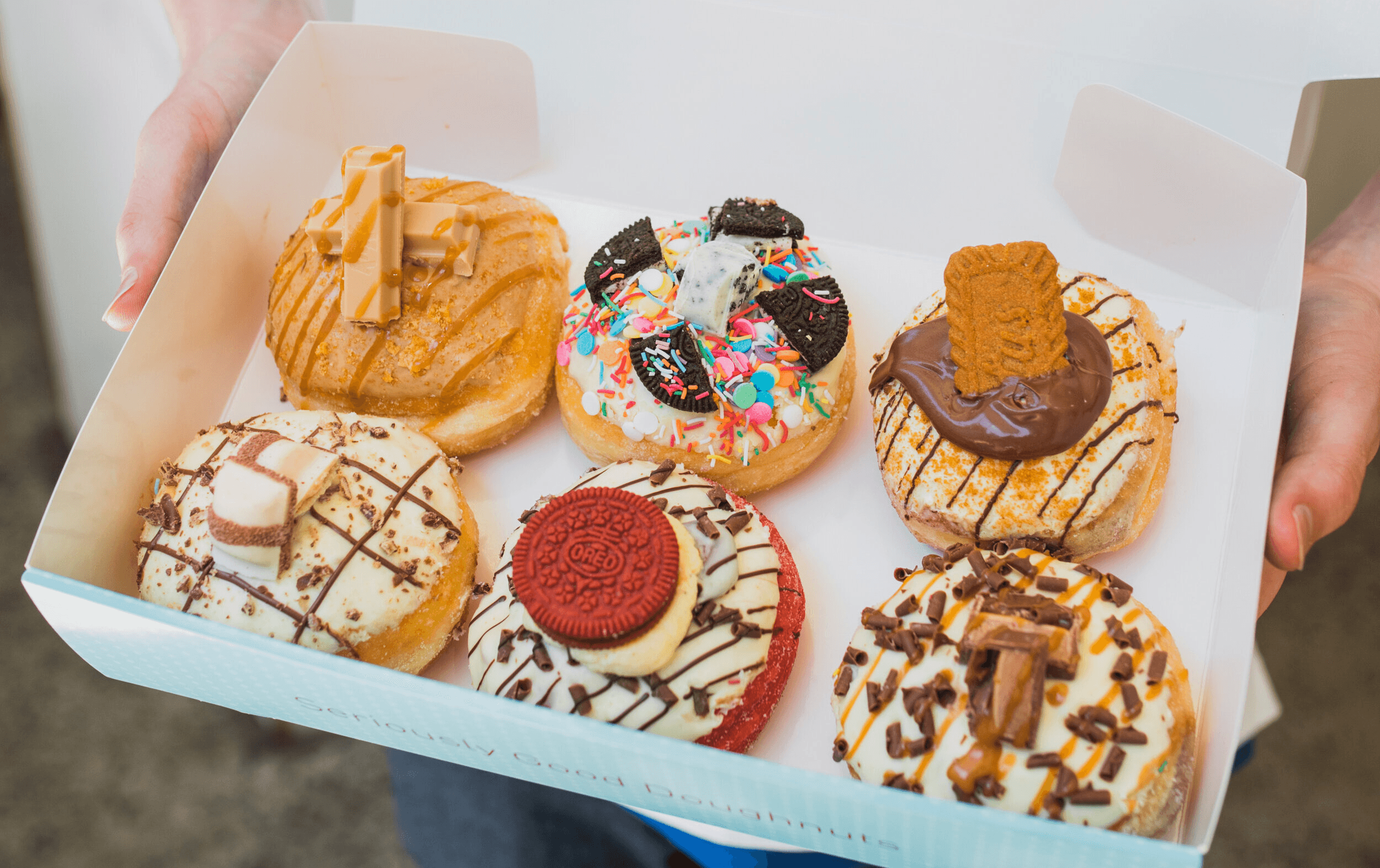 A box being held up filled with different of the best donuts Melbourne. 