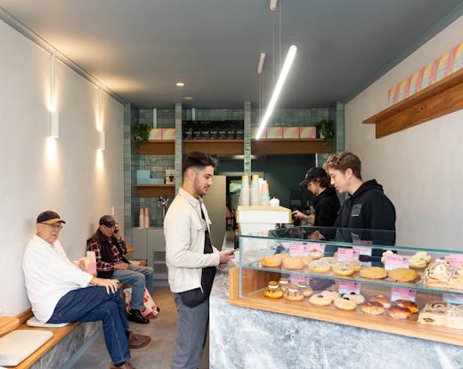 A shop with people sitting and a bar with doughnuts. 
