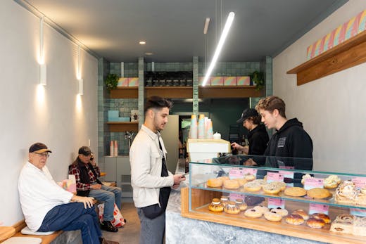 A shop with people sitting and a bar with doughnuts.