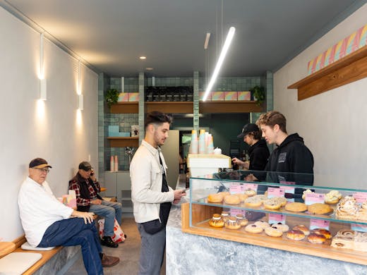 A shop with people sitting and a bar with doughnuts. 