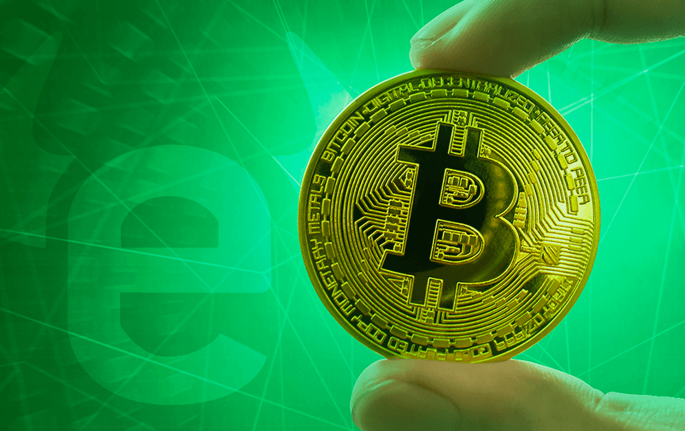 A person holding a single bitcoin-themed coin with a green background.