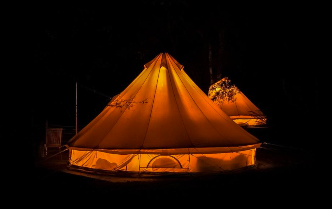 A glamping Victoria belle tent lit up at night. 