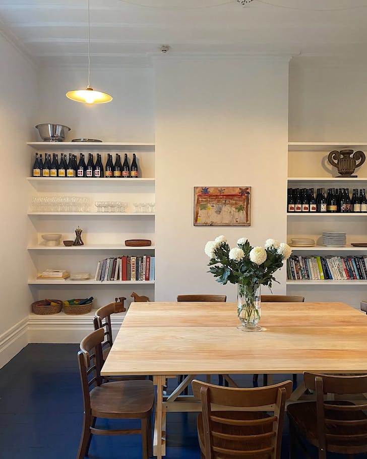 A cosy-looking dining room lined with wine bottles and a blue floor. 