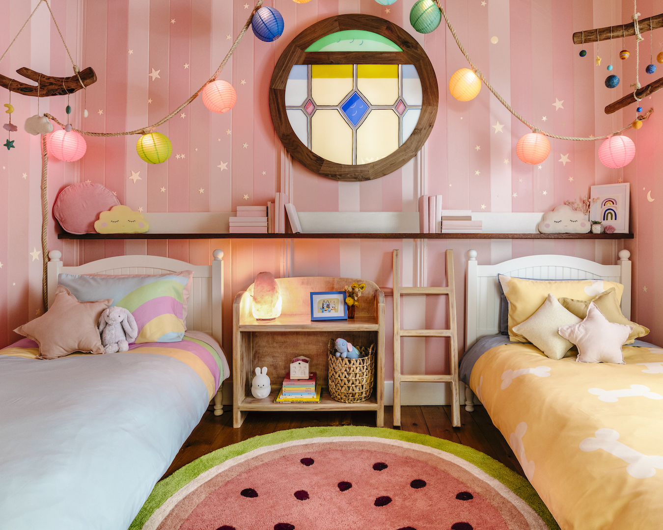 A pastel bedroom with two small beds and colourful lanterns.