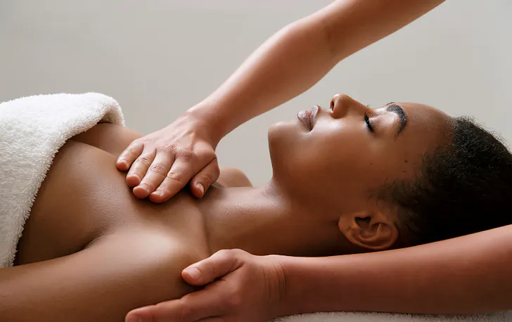 person being massaged on table in a white towel