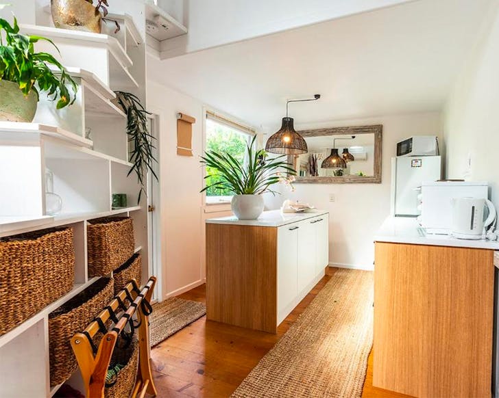 A cute kitchen area decorated with straw baskets, plants and lots of light at Boho Hill, one of the best winter cabins in NZ.