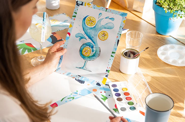 A woman holds up her painting.