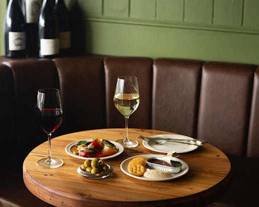 Two wine glasses and French-inspired snack plates are set on a table. 