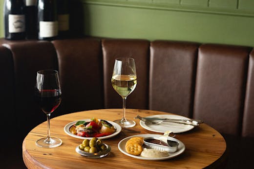 Two wine glasses and French-inspired snack plates are set on a table.