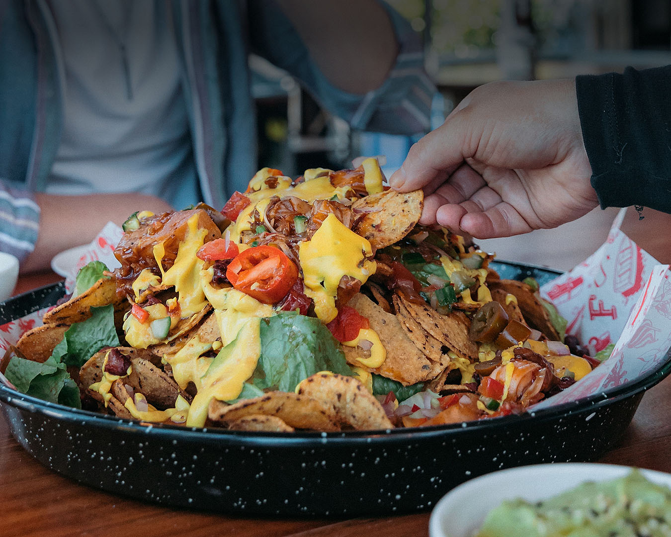 Someone digs into a pile of bottomless nachos.