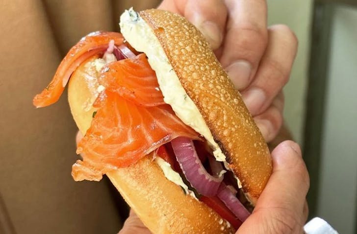 A person holding a best bagels Melbourne with two hands.