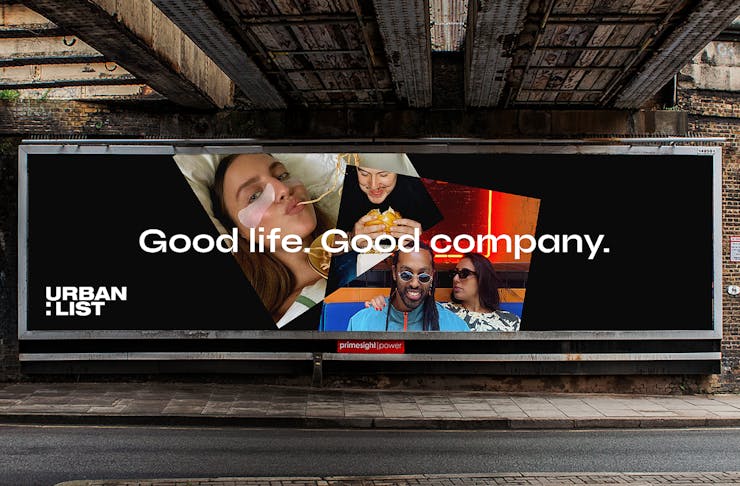 Image of a billboard with an Urban List logo, a black background, two images of people and the text 'Good Life. Good Company.'