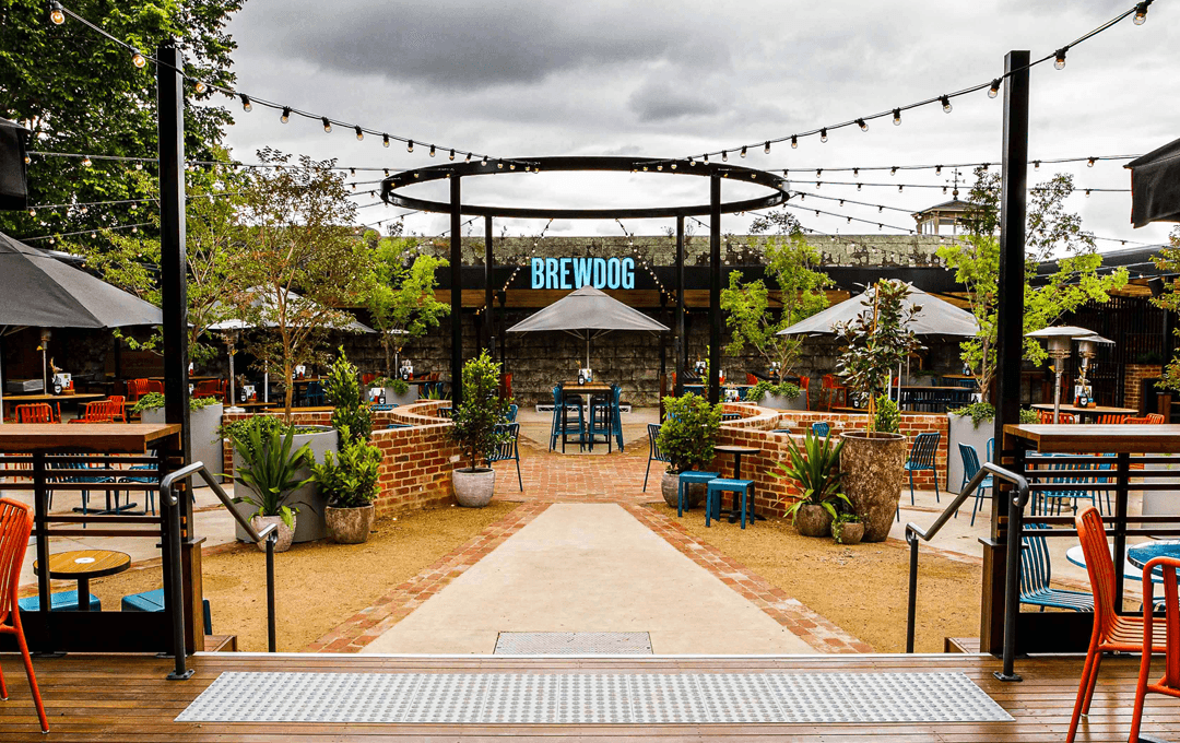 A beer garden with overhead lights and chairs and tables set up. 