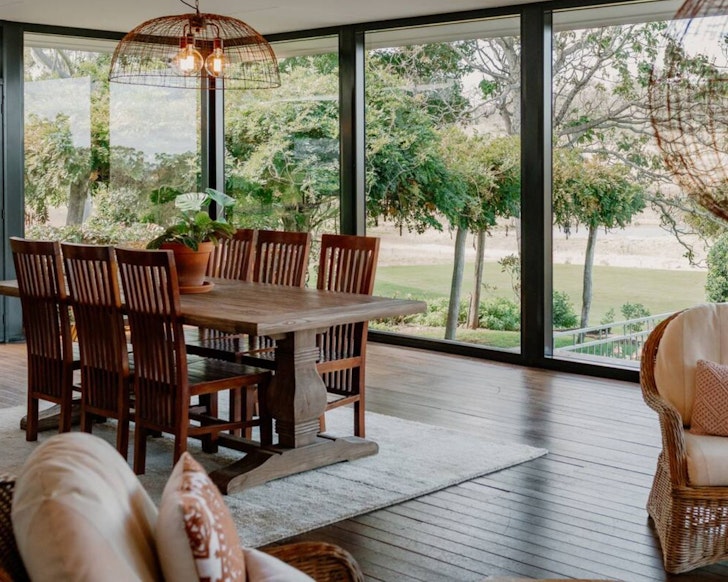 A wooden dining table by a window at Bunnyconnellen Homestead country stay near Brisbane