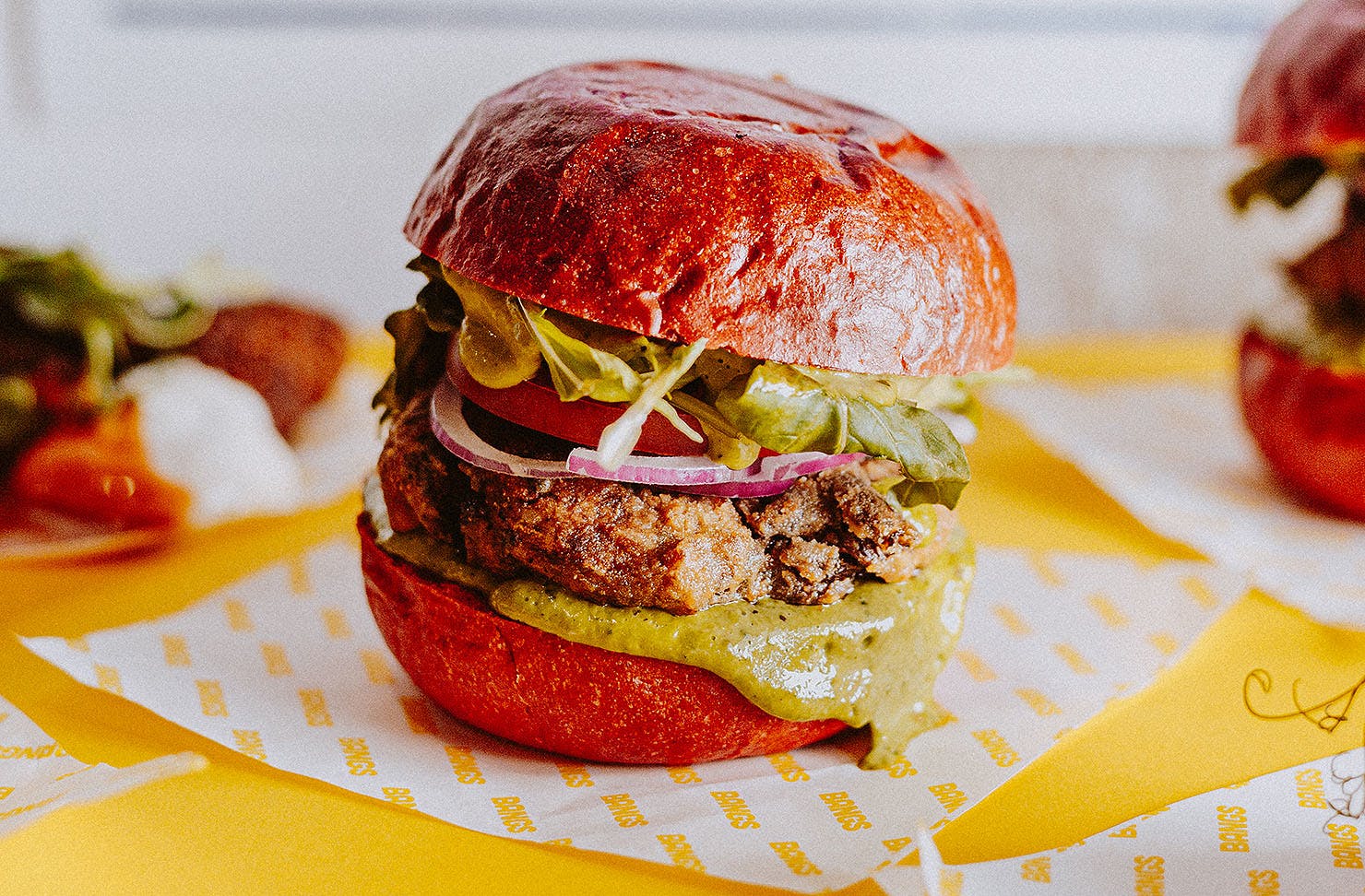 A shot of some delicious looking burgers boasting golden brown buns and extra sauce.