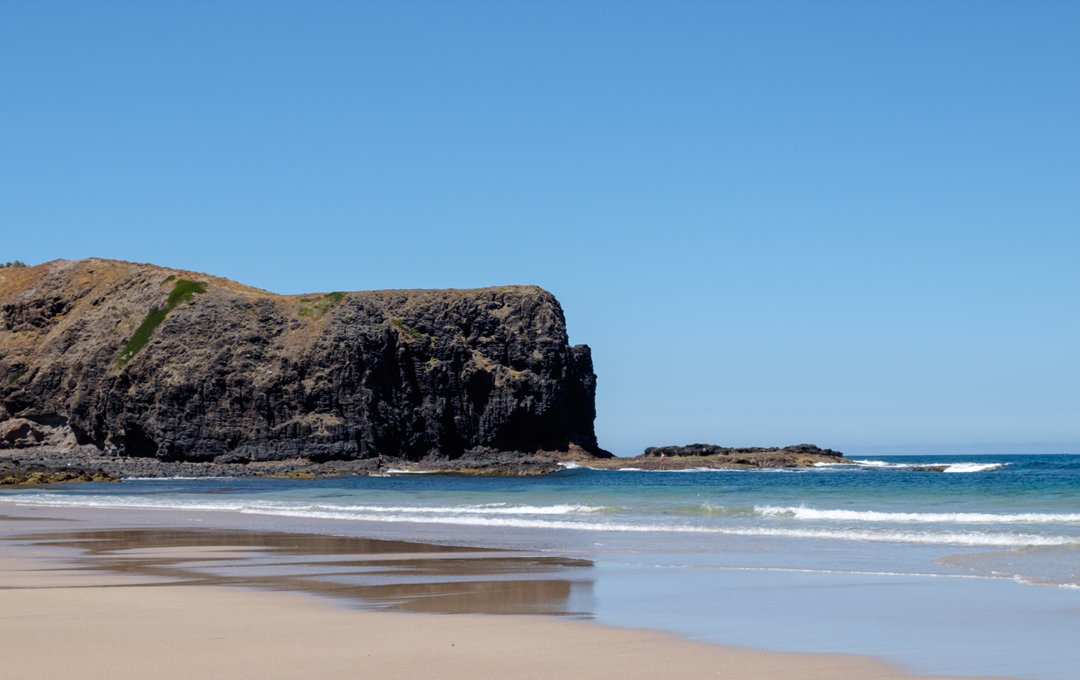 A bay ocean beach with a large rock at one the best walks in Victoria. 