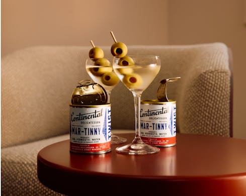 Two mar-tinny's, martini's in a can. In the centre are two glasses with martini and olives