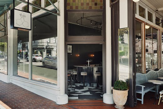 A shopfront with a sign and checkerboard floors inside.