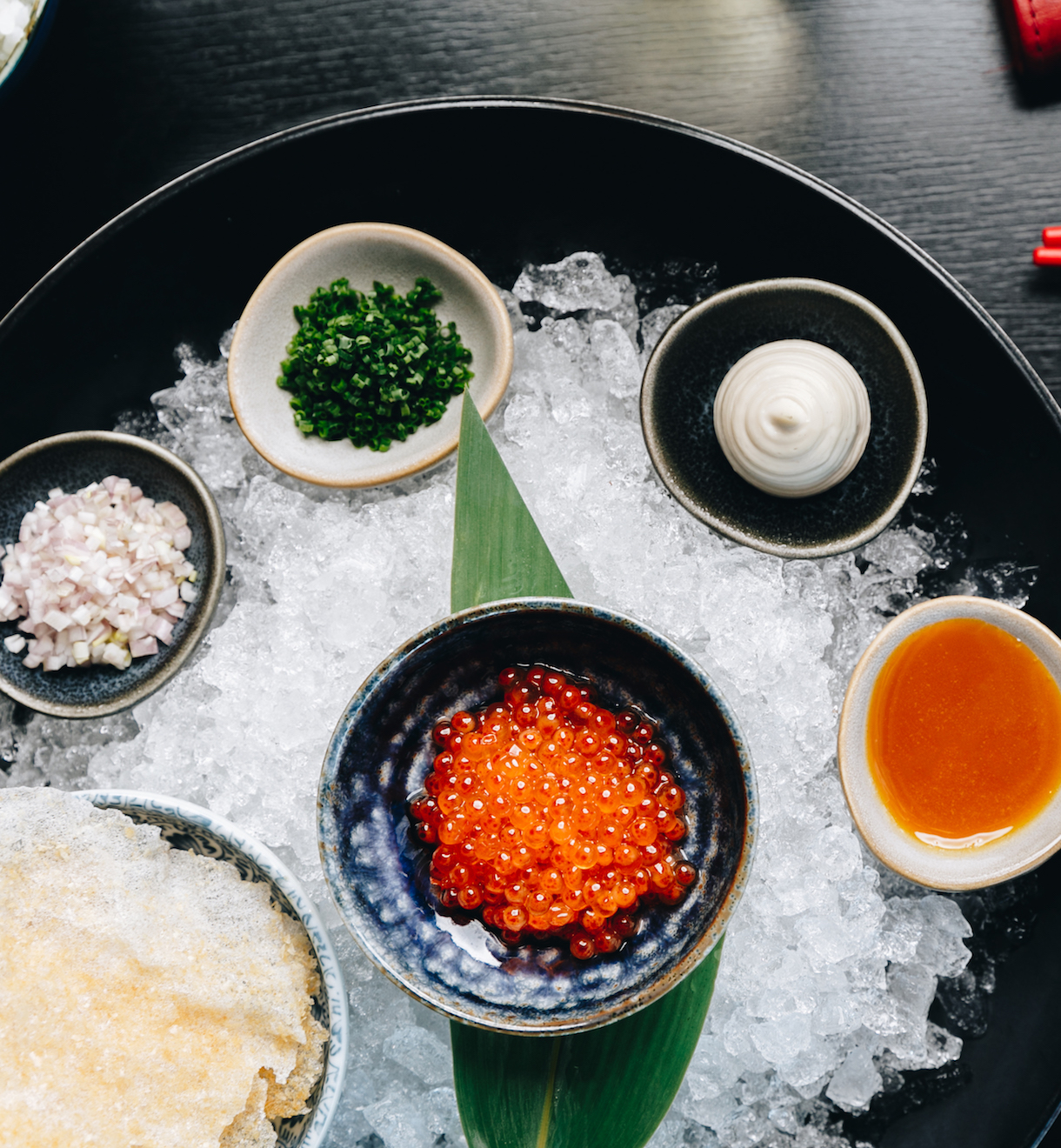 Small bowls of toppings and sauces sits atop a salted plate.