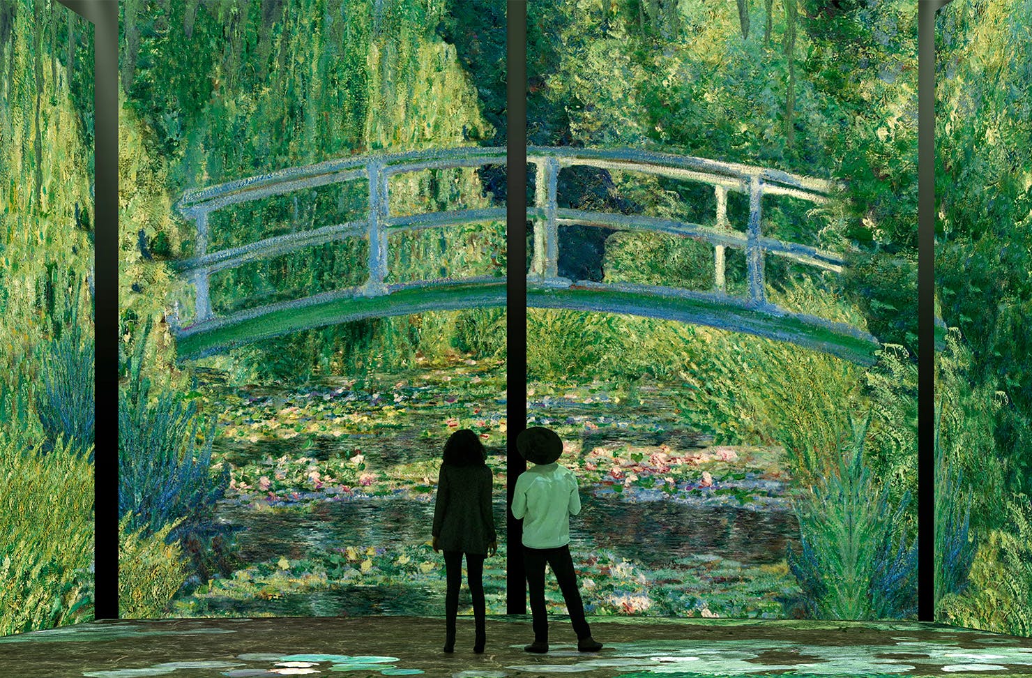 Two people standing in front of a large display of a bridge and water