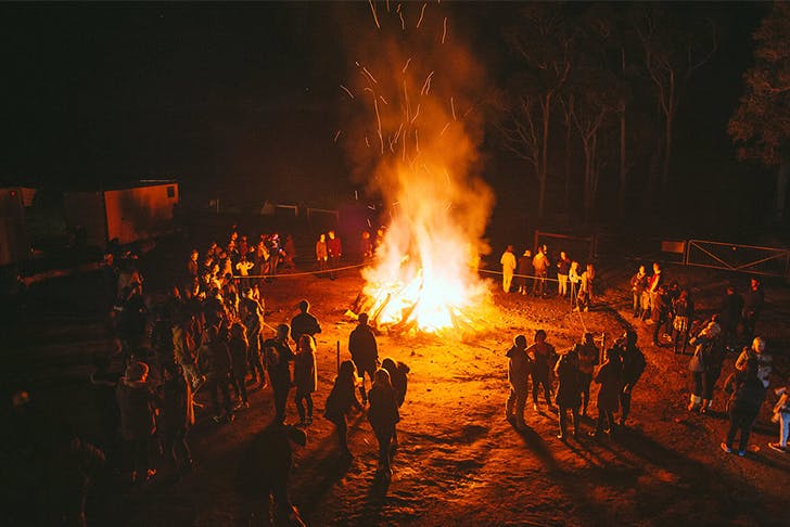 A bonfire with people standing in a circle around the edges
