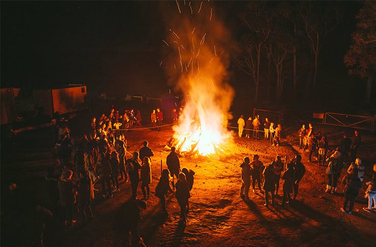 A bonfire with people standing in a circle around the edges