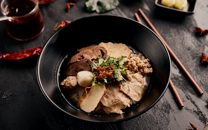 A bowl of soup with sliced pork, one of the best hot pot in Melbourne.