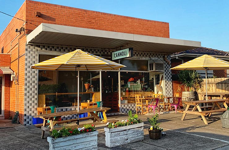 The exterior of Cannoli Bar shop with umbrellas and blue skies. 