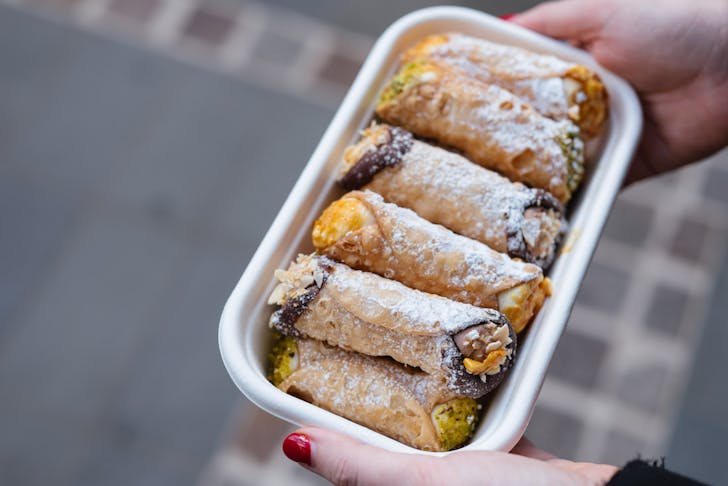 person holds tray of cannoli