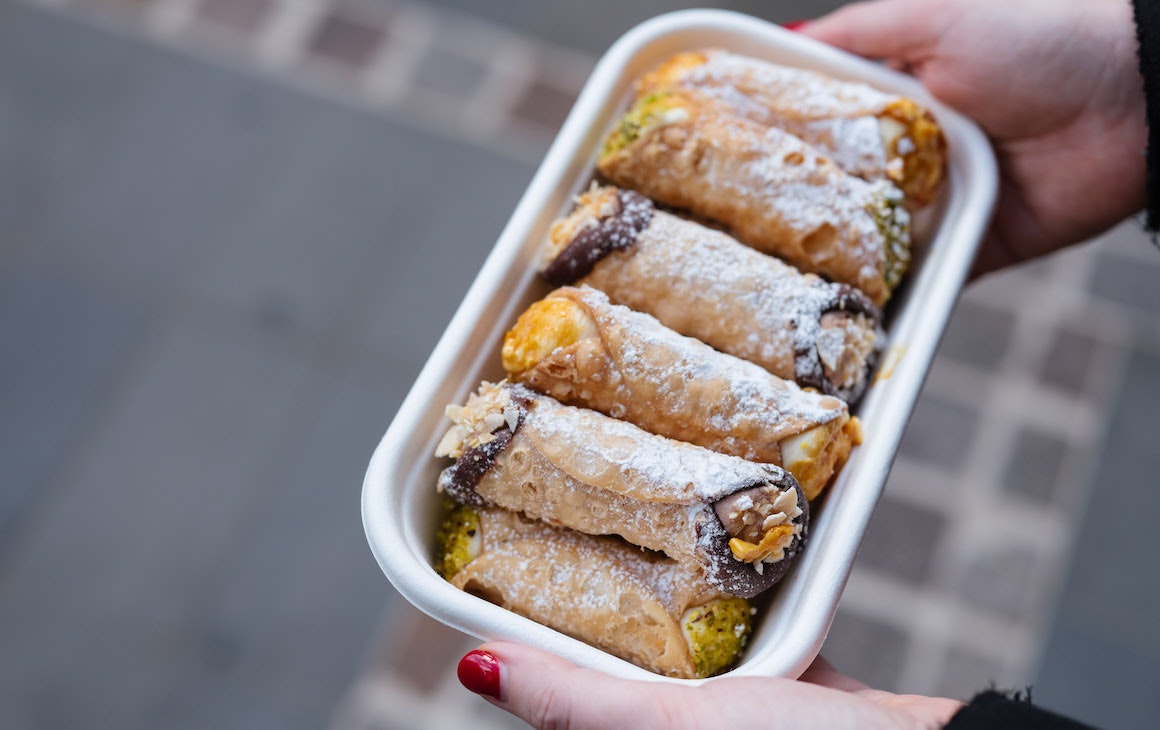 person holds tray of cannoli