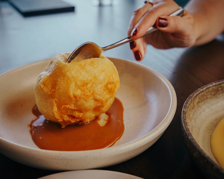 Kathryn Steane plunges a spoon into a globe of deep fried ice cream at Canting. 