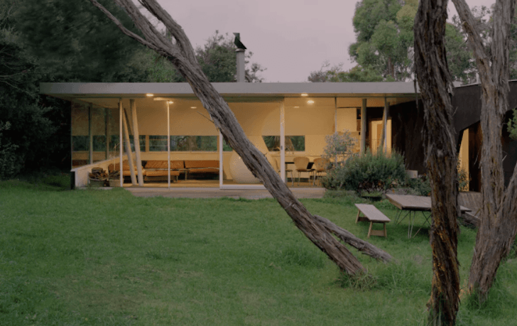 An art deco Airbnb Melbourne sits between trees with a lush green lawn.