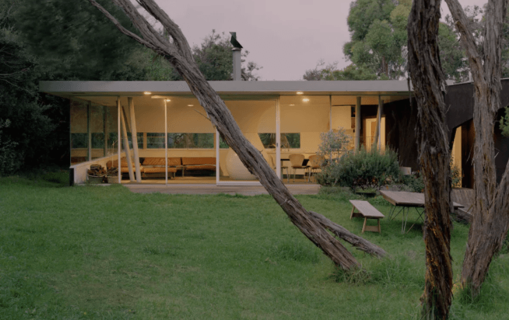 A house lit up at dusk with large glass windows, an accommodation mornington peninsula option.