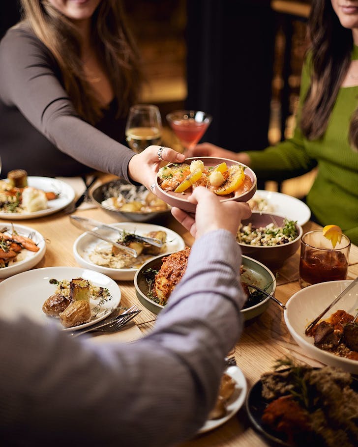 People enjoy a table laden with sharing dishes at Catalyst, one of the best restaurants in Dunedin.