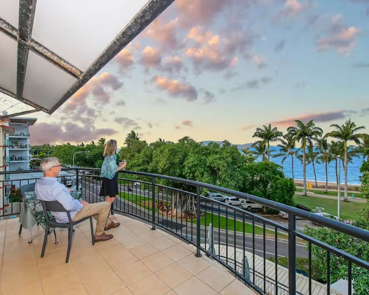 A couple looks out to sea from the balcony at Unit on The Strand Airbnb one of the best stays in Townsville