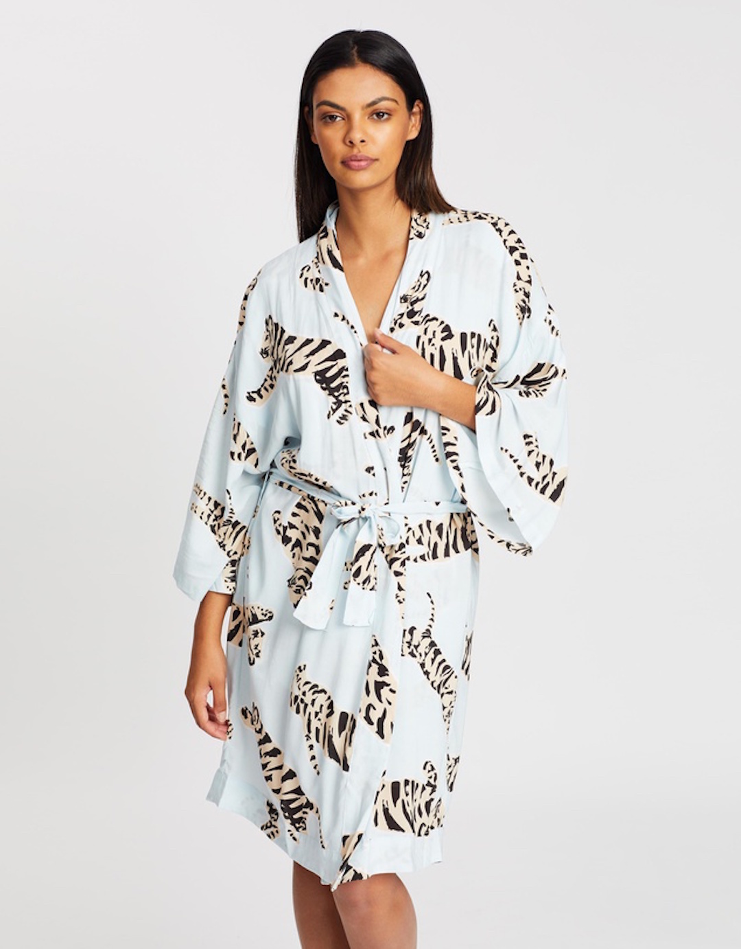 A woman poses wearing a blue dressing gown with a tiger print. 