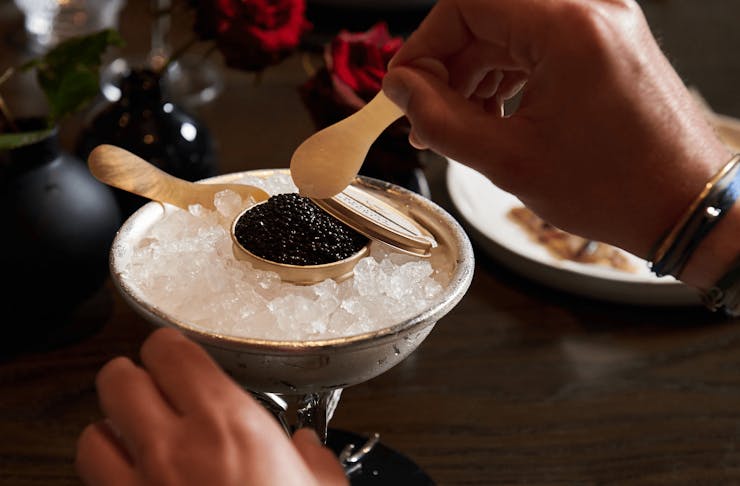 A person scooping a spoonful of caviar off a plate. 