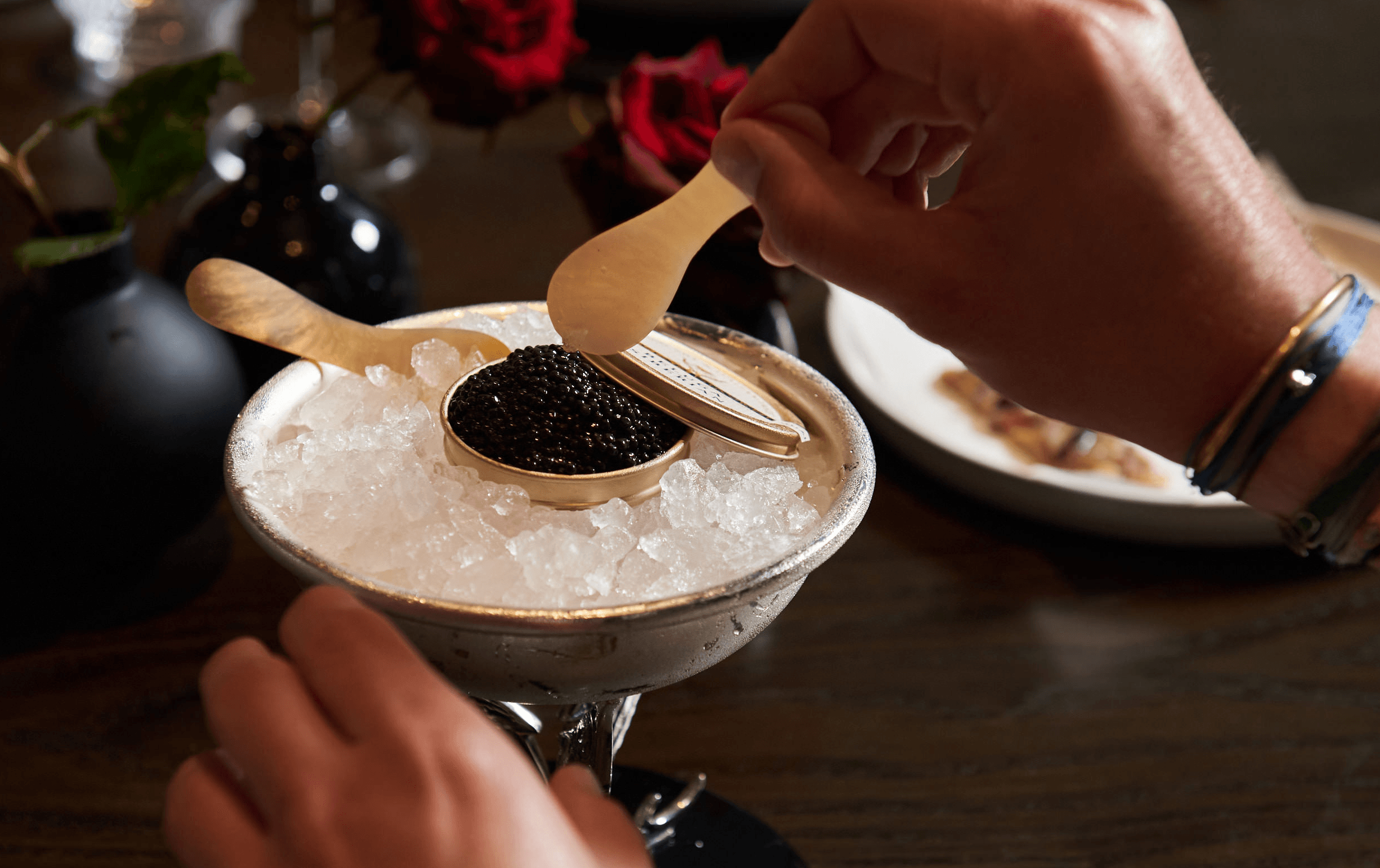 A person scooping a spoonful of caviar off a plate. 