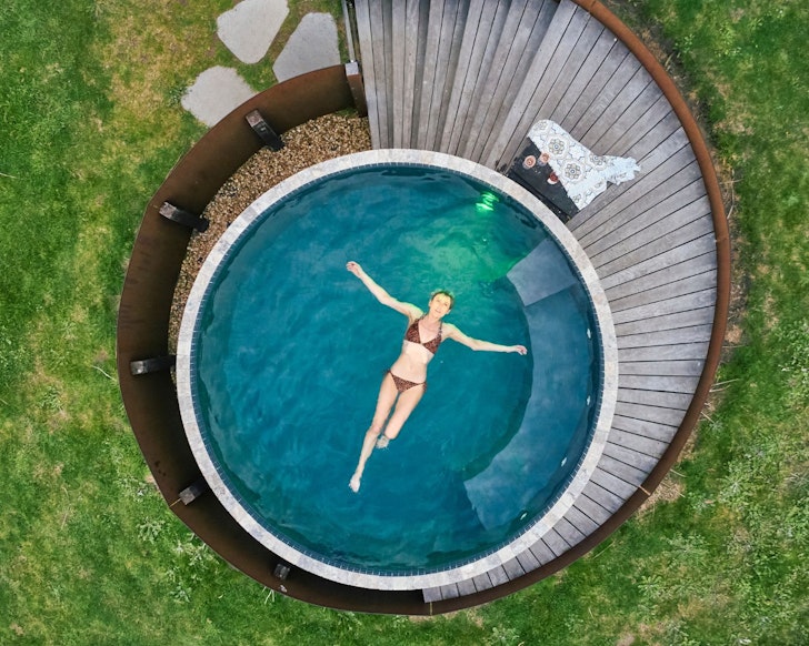 A woman lies in the outdoor spa at Charlson Farm one of the best large group Airbnbs Victoria