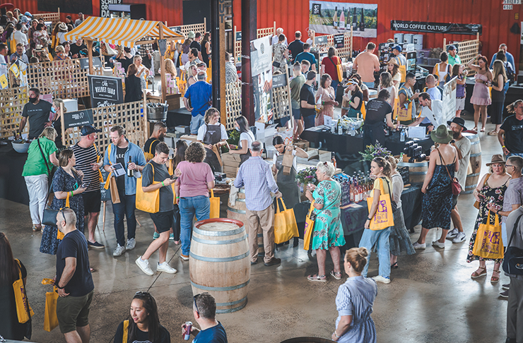 A warehouse full of people sampling some of Australia's best cheese and wine at a festival.