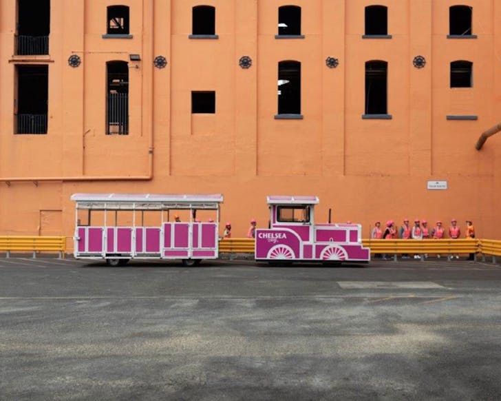 A hot pink train waits outside the sweet peach facade of the Chelsea Sugar Factory.