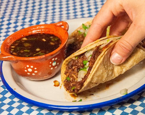 A person holding a taco on a plate. 